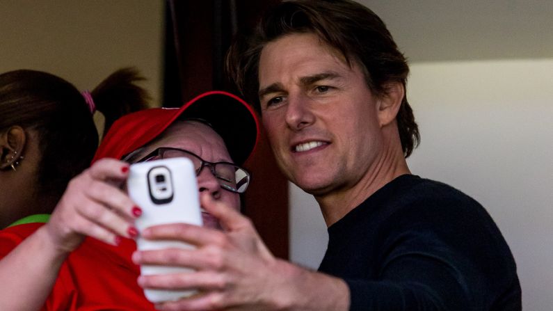 Actor Tom Cruise takes a photo with a fan while attending a Women's Final Four game in Tampa, Florida, on Sunday, April 5.