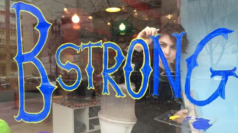 A worker writes "B Strong" on the window of Sugar Heaven, a shop near the Boston Marathon finish line.