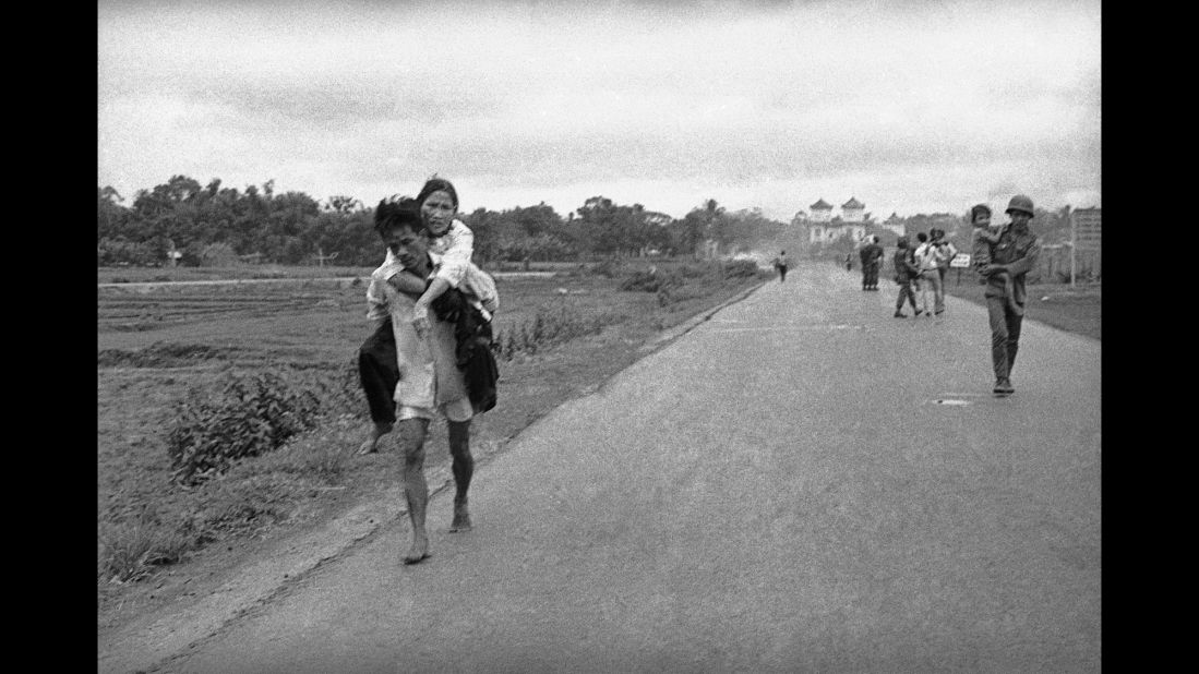 More injured people walk down the road.