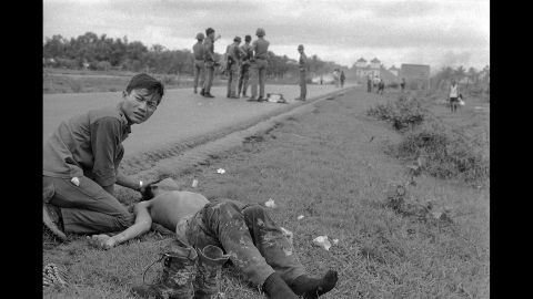 A South Vietnamese soldier crouches beside his friend who suffered severe napalm burns.