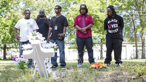 Darrell Mikell, Aaron Moses, Justin Lewis and Quin Dalton stand April 8 near the site where Scott was shot and killed. The person in the background is unidentified.