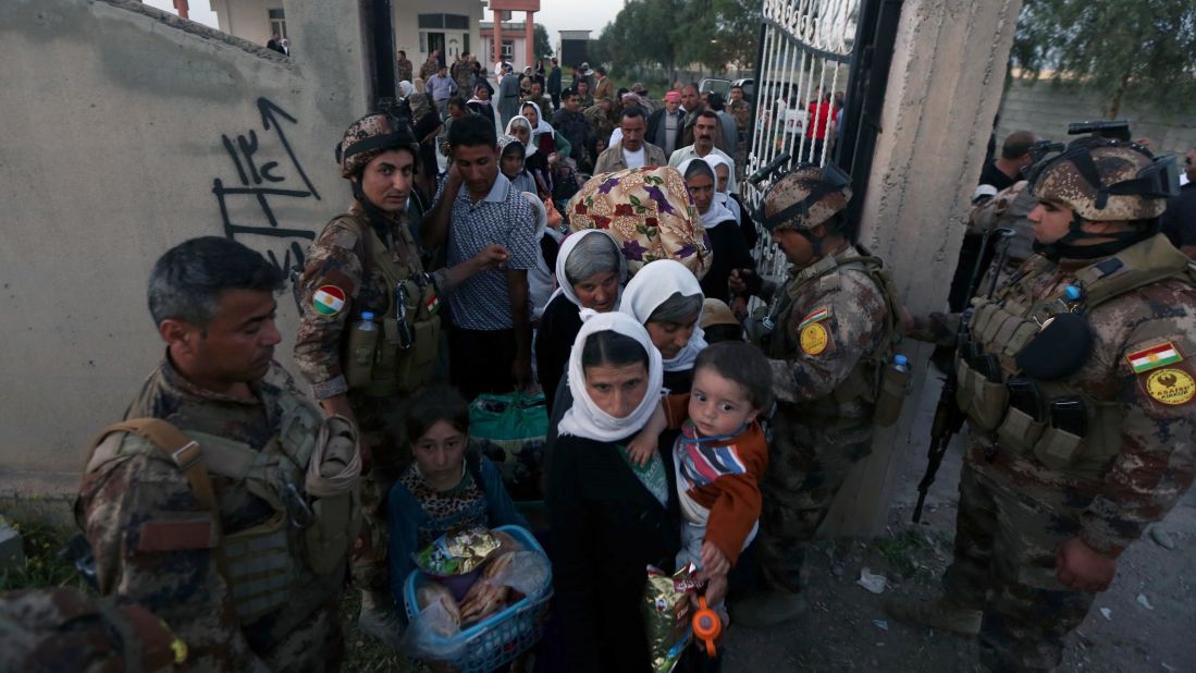 Kurdish Peshmerga forces help Yazidis as they arrive at a medical center in Altun Kupri, Iraq, on April 8.