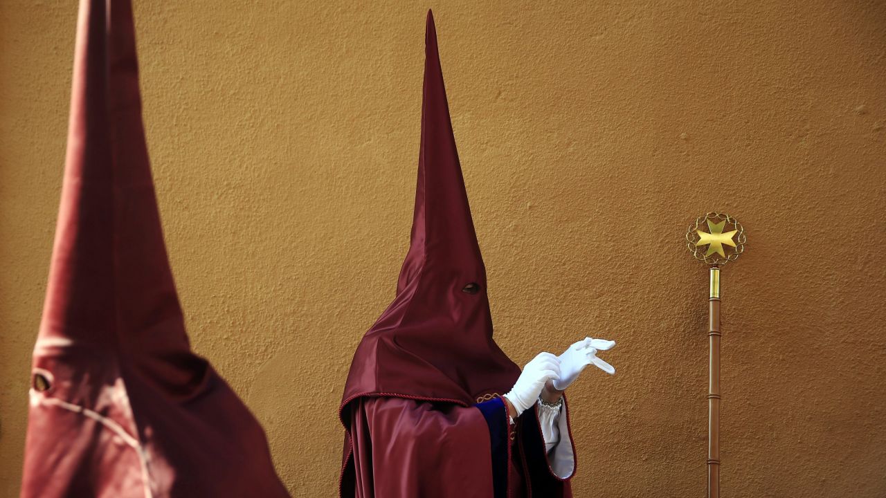 A penitent puts on his glove as he awaits the start of a Good Friday procession in Valencia, Spain, on April 3.
