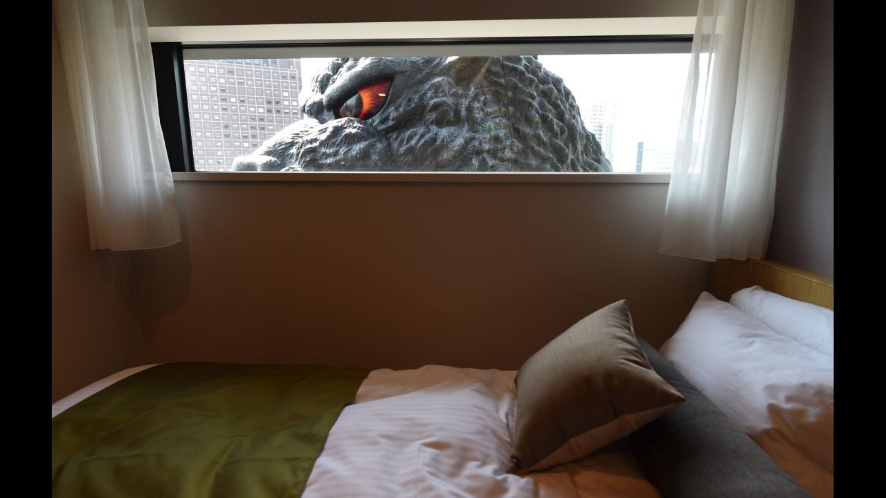 A Godzilla head is seen through a window of a hotel room in Tokyo on Thursday, April 9. The Godzilla is a main feature of the Hotel Gracery Shinjuku, which opens this month.