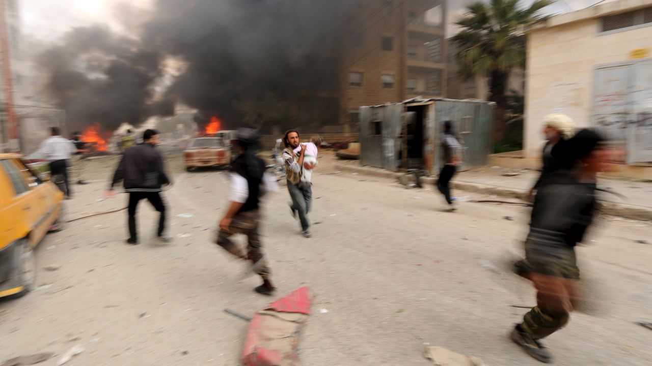 A man in Idlib, Syria, runs with an injured child after what activists said was shelling by forces loyal to Syrian President Bashar al-Assad on Sunday, April 5.
