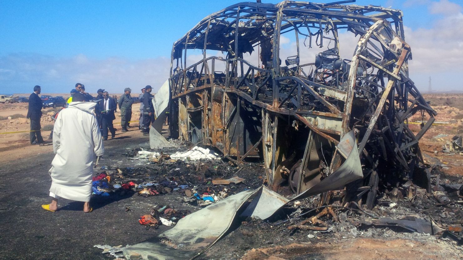 Officials check out the remains of a bus following a fire and fatal crash Friday near Tan-Tan, Morocco.