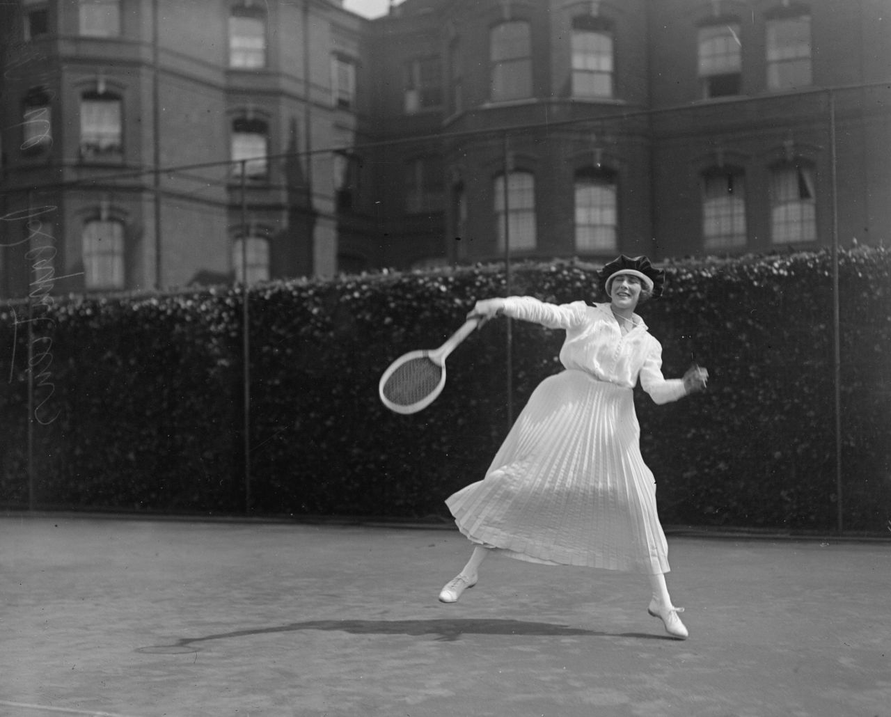 A young lady enjoys a hit at the Queen's Club lawns in London, 1918, dressed in a long pleated skirt and stockings.<br />"Tennis started out in the Victorian era in England as a lawn sport for the aristocracy," says Rothenberg.<br />"It would be something that happened at social occasions; people would string up a net just in the front lawn of their manor, and they would play in fairly similar attire to what they were wearing at the time."