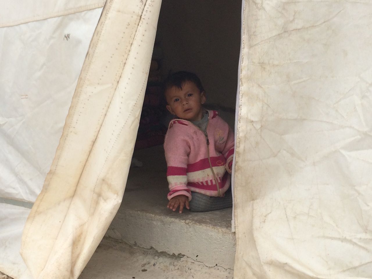 A small child is seen within the safety of a tent at the refugee camp. It's not known how long they'll have to stay here.