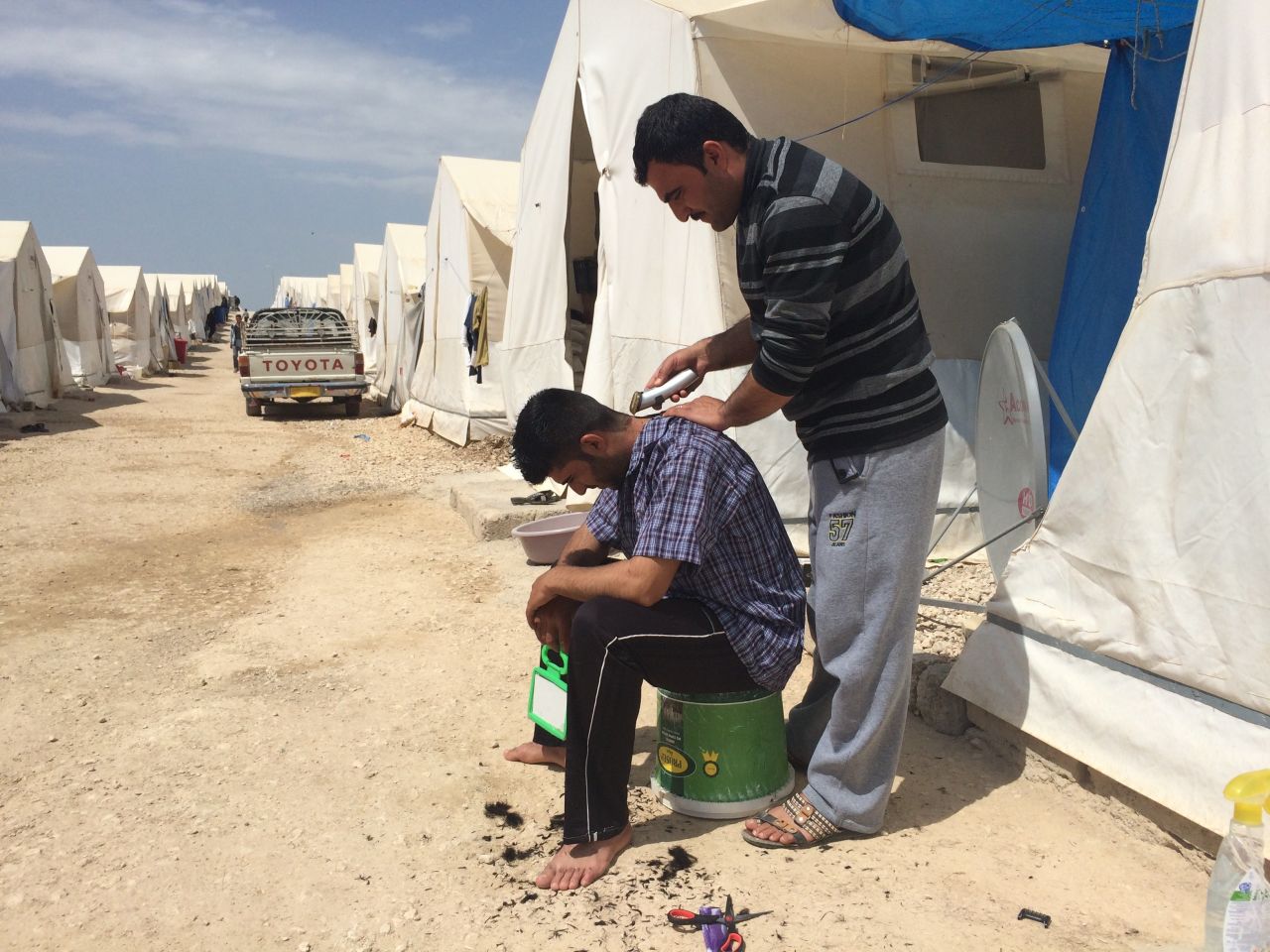 A man gives another a shave. For many, an element of normalcy has returned after months in the camp. 