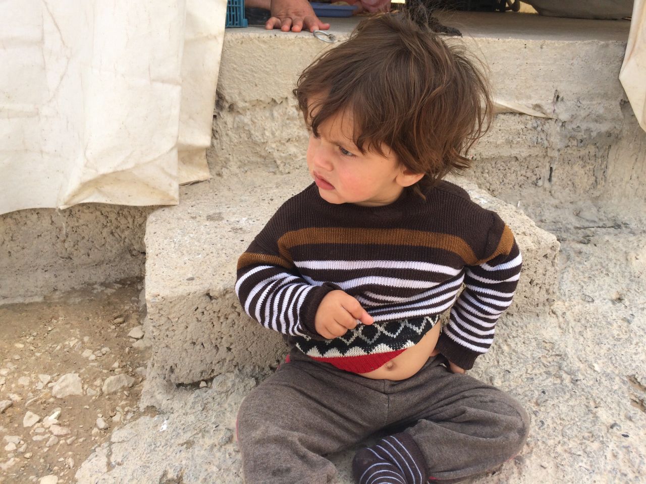 A small boy sits on the ground at Shariya refugee camp in Duhok, in Iraqi Kurdistan. It's home to thousands of Yazidis, many who fled from Mount Sinjar and surrounding towns when ISIS fighters moved in.