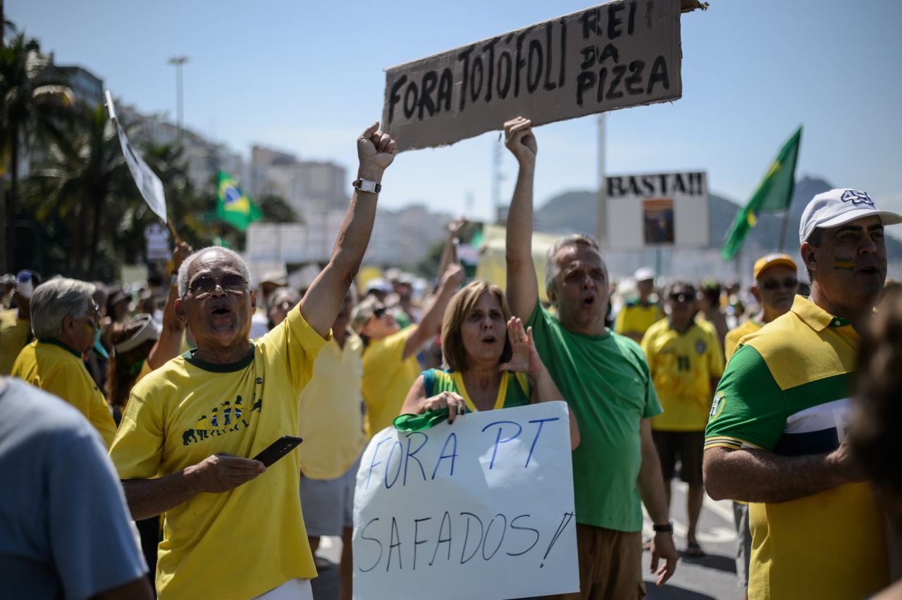 People hold signs reading "Workers' Party out" at Copacabana beach. 