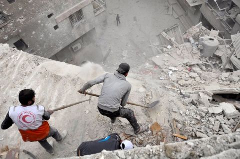 Volunteers scoop debris off a building that was hit by a bomb in early April in the Yarmouk Palestinian refugee camp near Damascus, Syria.