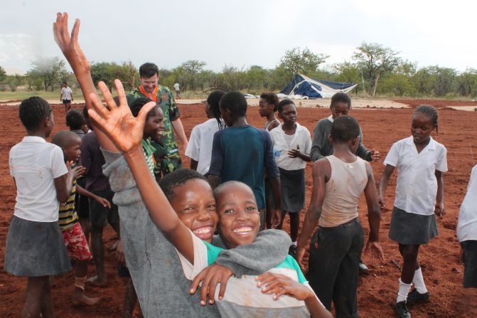 Children from the Okaukuejo school join Global United players for a kickabout, with Gorlitz visible in the background.