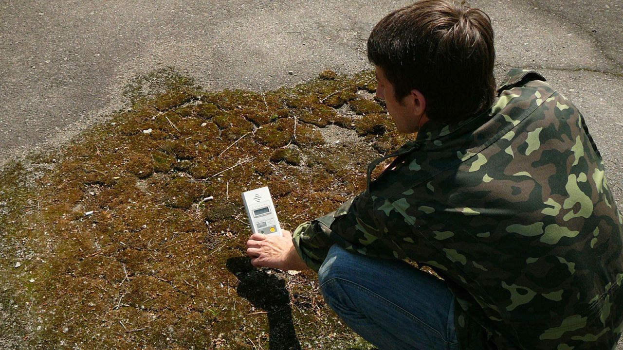 A guide tests radiation levels inside the Chernobyl Exclusion Zone.