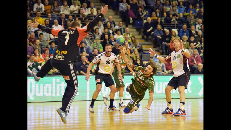 Fredrik Raahauge Petersen, a handball player with the German club Fuchse Berlin, tries to throw the ball past TuS Nettelstedt-Lubbecke's Nikola Blazicko during a match played Wednesday, April 8, in Berlin.