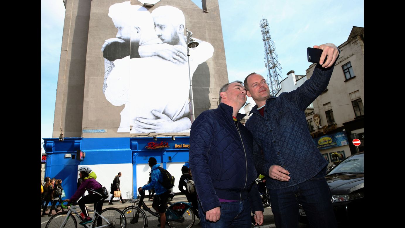A couple in Dublin, Ireland, pose for a photo in front of a new mural by Irish artist Joe Caslin on Saturday, April 11. Ireland is having a referendum next month on whether to legalize same-sex marriage.