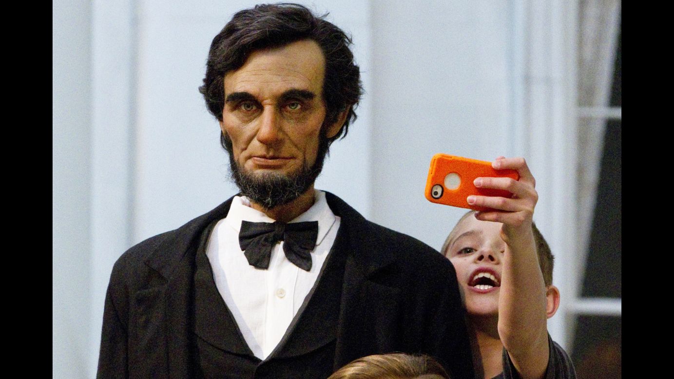 A boy stretches to take a selfie with a life-size figure of former U.S. President Abraham Lincoln at the Lincoln Presidential Museum in Springfield, Illinois, on Wednesday, April 8.