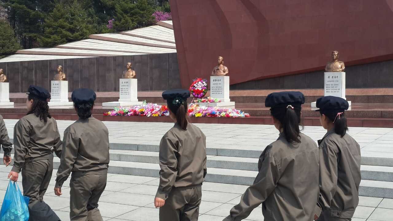 Personas caminan en fila frente a las estatuas del Cementerio de los Mártires Revolucionarios. 