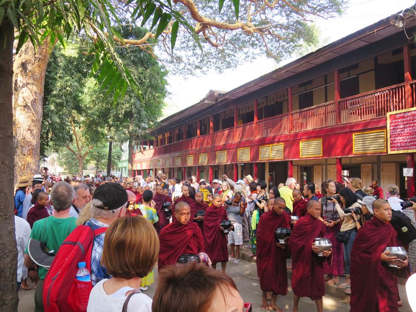Around 10 a.m. each day, tourists gather on the side of the road at Mahagandhayon Monastic Institution in Amarapura, Myanmar, waiting for the appearance of the monastery's monks.