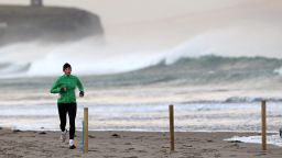 A jogger runs along the shoreline in Portstewart in Northern Ireland, on December 24, 2013. A man and a woman died in separate river incidents on Monday as high winds and heavy rain lashed Britain, disrupting transport as people headed home for the Christmas holidays. AFP PHOTO / PETER MUHLY (Photo credit should read PETER MUHLY/AFP/Getty Images)