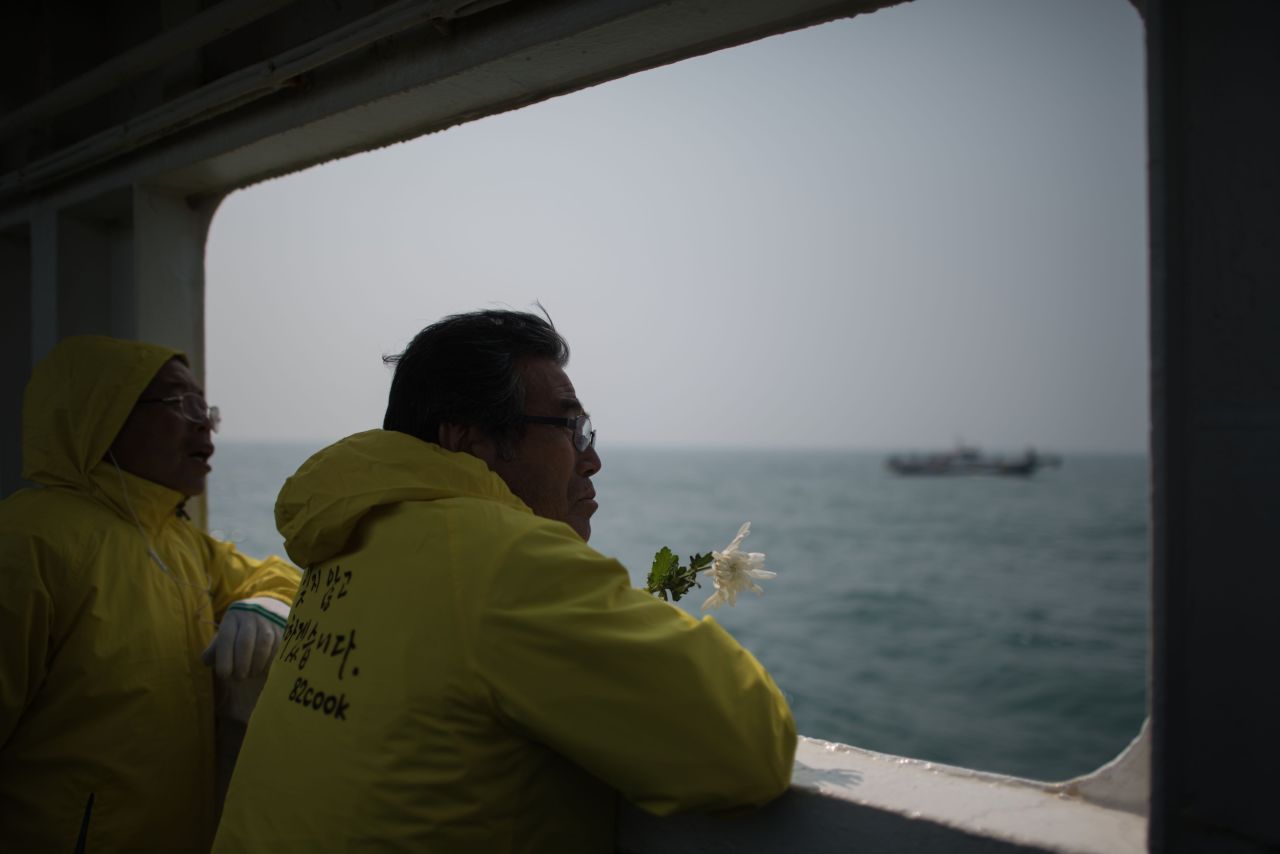A man hold a flower as he stands on the deck of a boat during a visit to the site of the sunken Sewol ferry, off the coast of South Korea's southern island of Jindo.