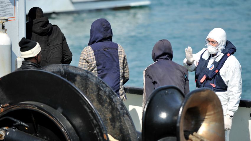 An Italian coast guard looks at people disembarking from the tanker Maria Bottiglieri, during the landing operations of more than 110 Central African migrants, men and women, on April 15, 2015 in the port of Corigliano Calabro.