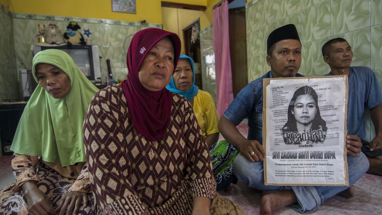 Family members of Indonesian maid Siti Zainab hold a poster of her at their home in Bangkalan in East Java, April 15, 2015.