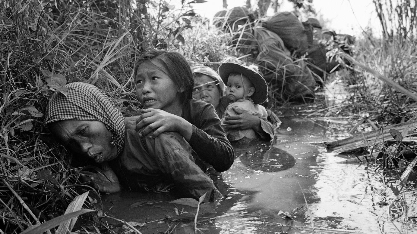 Women and children crouch in a muddy canal as they take cover from intense Viet Cong fire at Bao Trai, about 20 miles west of Saigon, in January 1966.