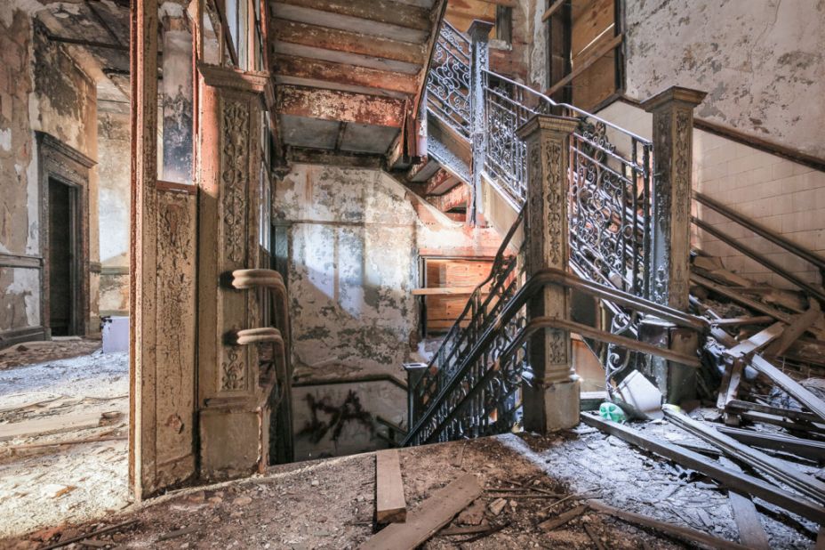 A staircase retains some elegant wrought-iron details at the long-abandoned P.S. 186 school in Harlem. After 40 years of neglect, saplings sprout from the upper floors.
