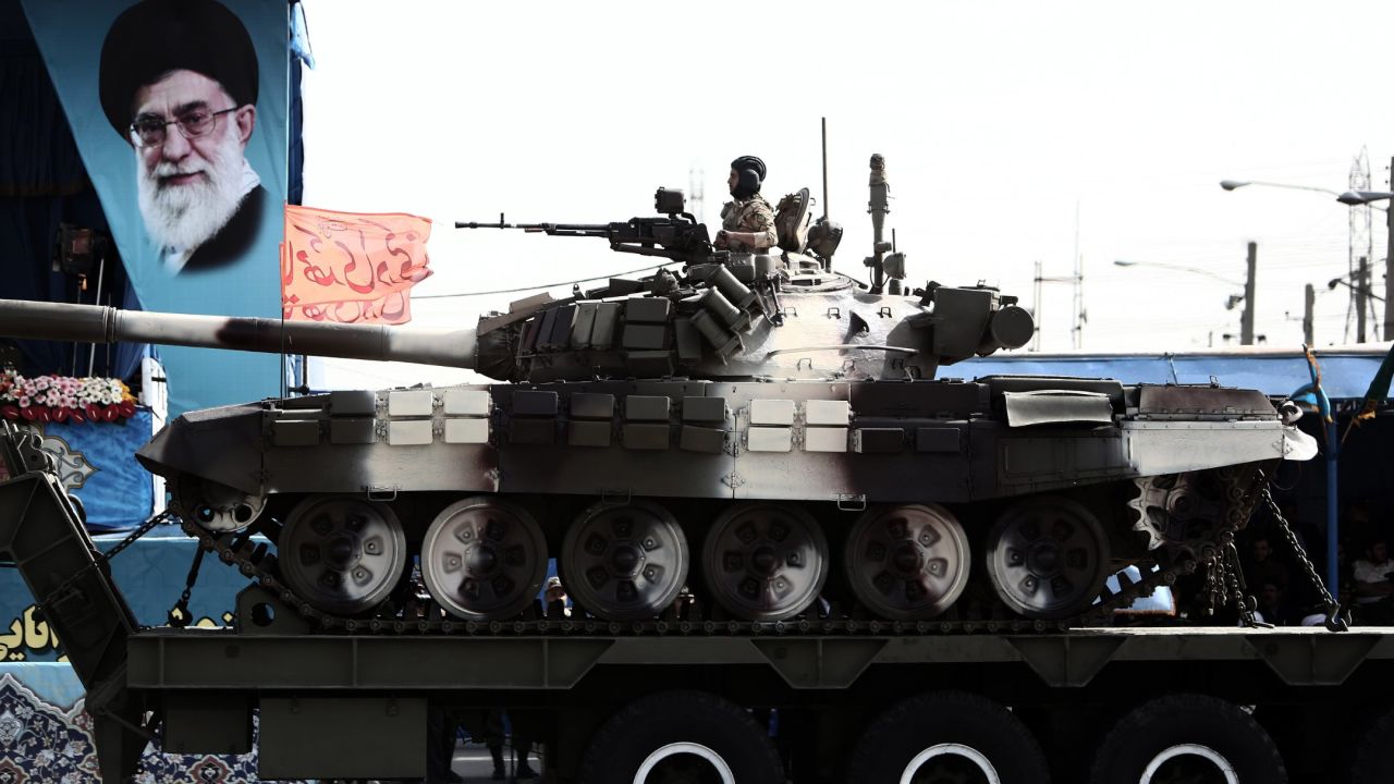 A soldier sits atop a T-72 tank as it rolls past a portrait of Supreme Leader Ayatollah Ali Khamenei on April 18.