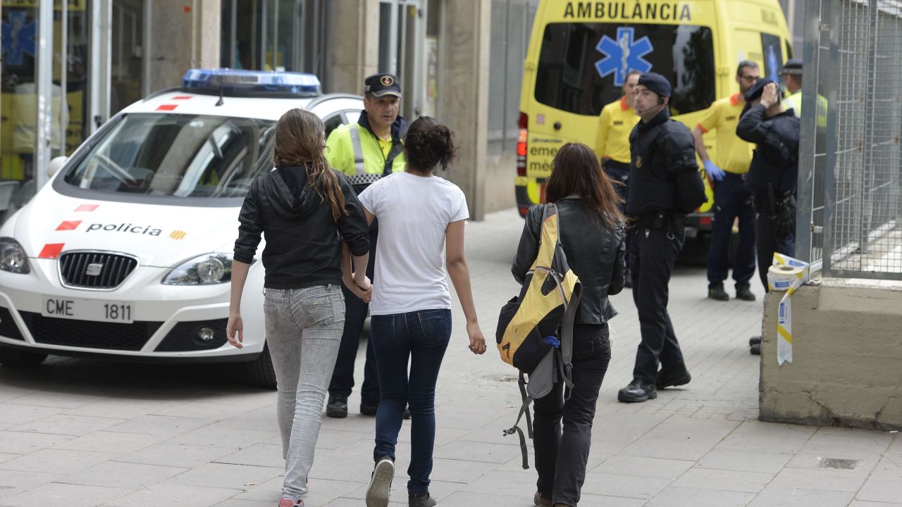 Young girls walk towards Police officers at the Joan Fuster Institue in Barcelona on April 20, 2015 after a student allegedley broke into the school armed with a crossbow killing a teacher and wounding four others. A student under 14 years was arrested today by police on suspicion of having killed a teacher from the school in northeastern Spain in Barcelona and wounding four people, a police spokesman.