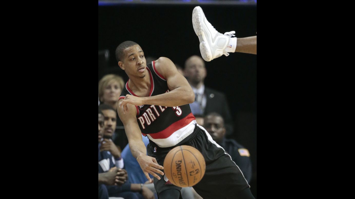 Portland guard C.J. McCollum passes under the outstretched leg of Memphis' Tony Allen during an NBA playoff game Sunday, April 19, in Memphis. Memphis won the first game of the series 100-86.