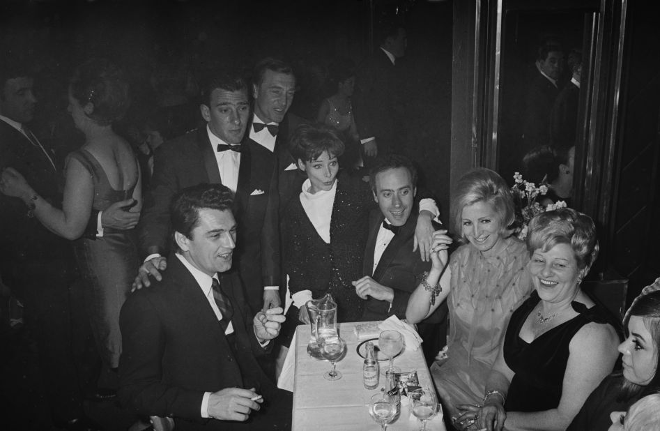 Frances Shea (1943 - 1967, far right) with her husband, English gangster Reggie Kray (1933 - 2000, standing, third from left) and celebrity guests at the El Morocco, a nightclub owned by the Kray Twins, in Soho, London, 30th April 1965. Kray has his hand on the shoulder of British actor Edmund Purdom (1924 - 2009). At centre is Actress Adrienne Corri with her arm around Welsh actor Victor Spinetti (1929 - 2012). The Kray twins' mother, Violet Kray, is second from right.