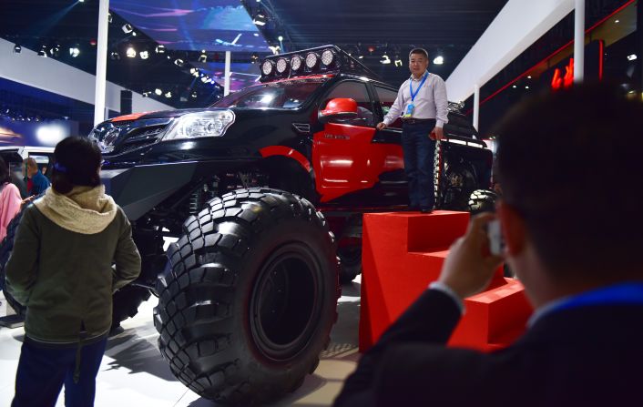 A man poses next to a monster pick-up truck made by Chinese company Foton Motor  at the Shanghai Auto Show on April 20, 2015. 