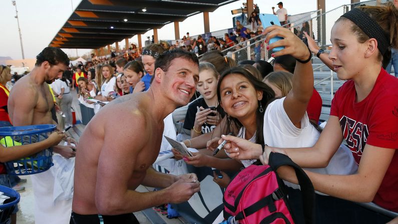 A fan takes a photo with swimmer Ryan Lochte after a race Thursday, April 16, in Mesa, Arizona. At the far left is Michael Phelps, who was returning to the pool after a six-month suspension.