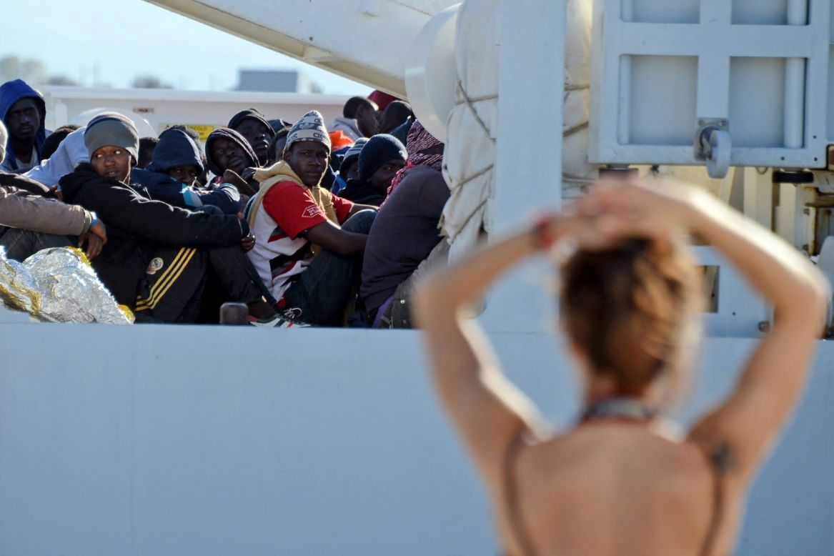Shipwrecked migrants sit on the deck of a rescue vessel as they arrive in the Italian port of Augusta on Thursday, April 16.