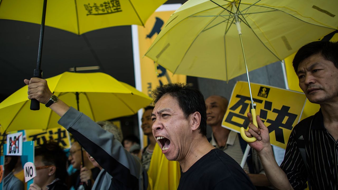 Pro-democracy protesters hold yellow umbrellas, a symbol of Hong Kong's Occupy movement, during a demonstration outside the city's Legislative Council on April 22, 2015.