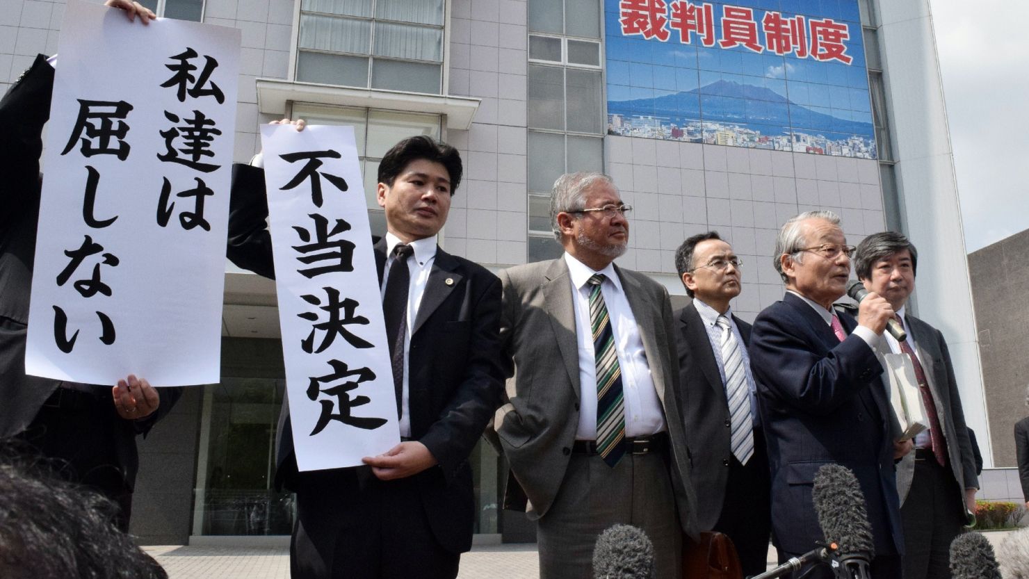 Japanese lawyers show banners with 'unfair ruling' in front of the Kagoshima district court in Kagoshima, Japan's southern island of Kyushu on April 22, 2015. 