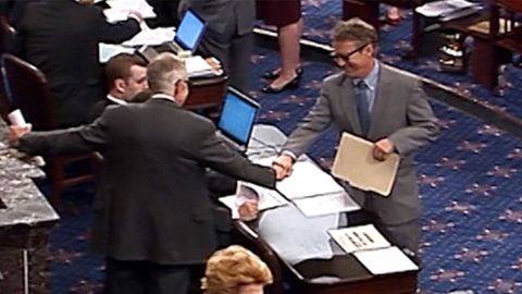 Rand Paul and Harry Reid fist bump while wearing sunglasses on the Senate floor.