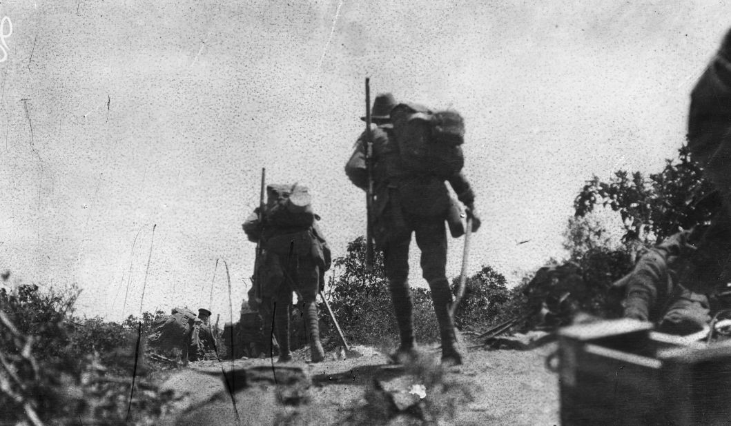 This image shows Australian troops crossing Plugge's Plateau after the landing on 25 April, at about midday. The men in front are thought to be kneeling in the scrub. The troops were under fire from the other side of Shrapnel Valley. This scene is from a captured Turkish trench overlooking the beach at Anzac Cove.
