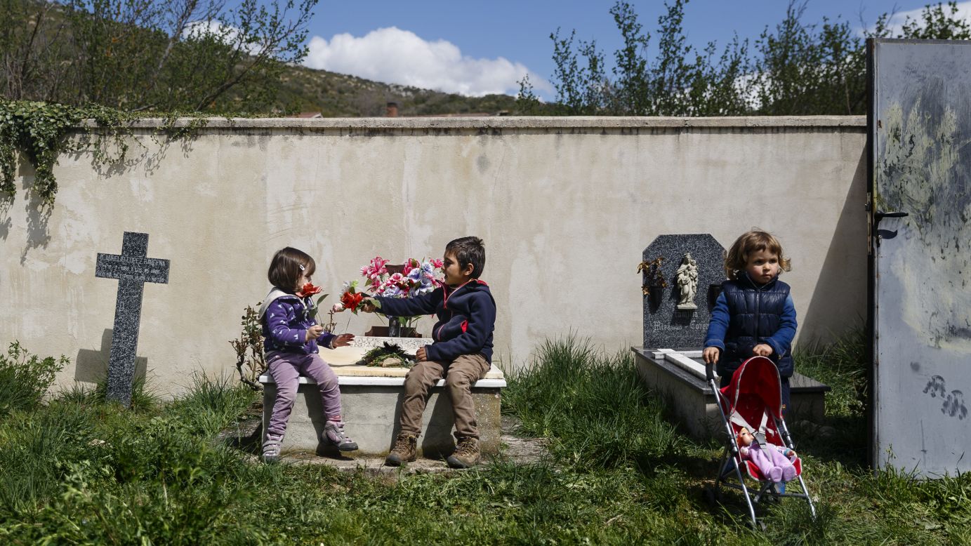 A boy gives a flower to a girl while sitting on a tomb in Valdenoceda, Spain, on Saturday, April 18.