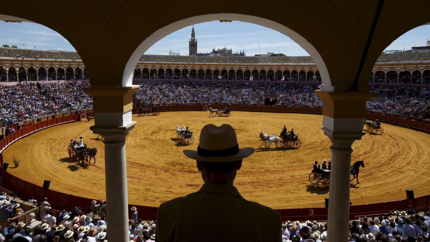 A man in Seville, Spain, watches a carriage exhibition Sunday, April 19, in the Maestranza bullring.