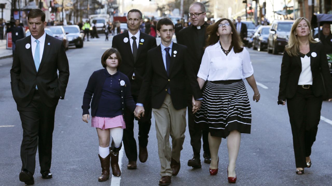 <strong>Jane Richard</strong>, in the pink skirt, lost her leg. She holds the hand of her brother Henry as they walk down Boylston Street with their parents and others after an April 15 ceremony this year. She was standing next to her brother Martin behind a metal barricade when the second bomb went off. Her father, Bill, took one look at Martin, knew he wouldn't make it and focused his efforts on saving Jane. She sang in April at Fenway Park on opening day. 