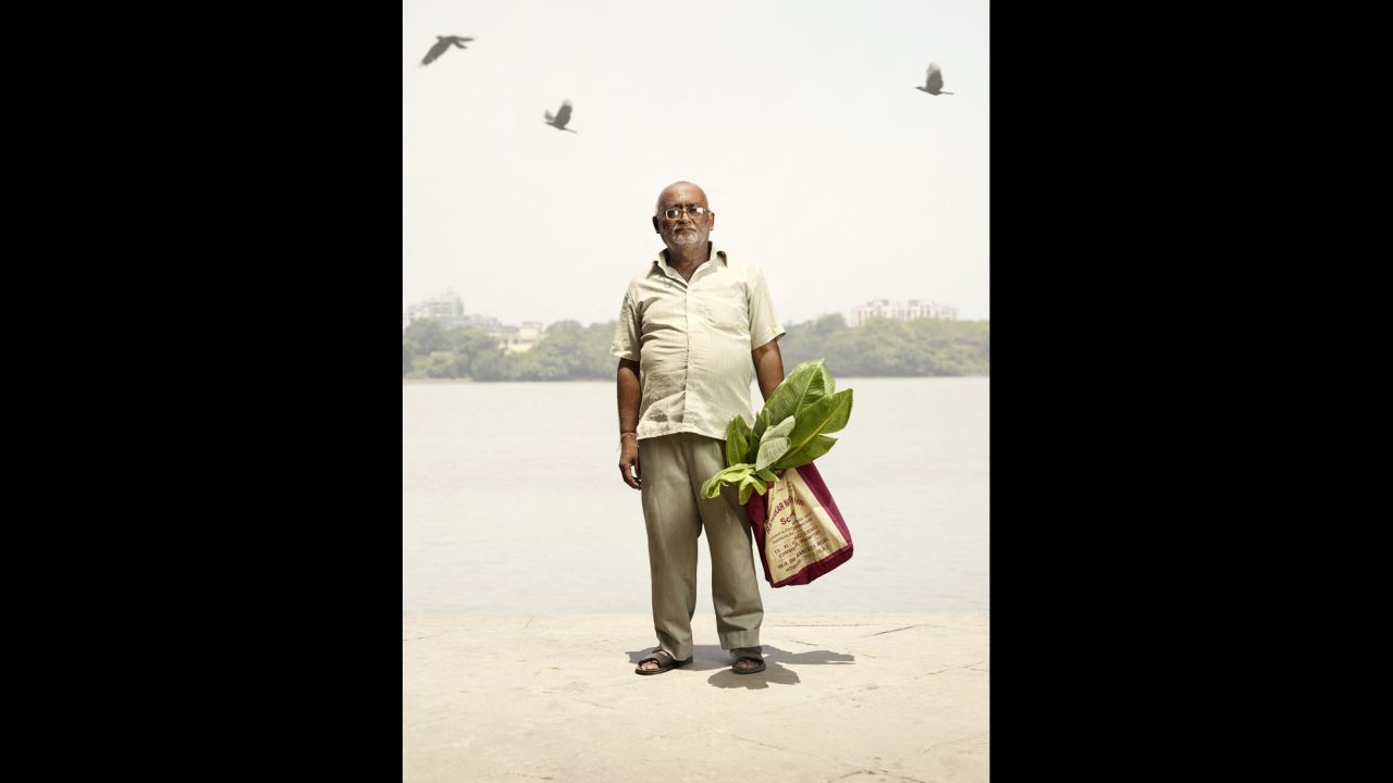 Prakash Singh stands for his portrait as birds are seen in the sky. 