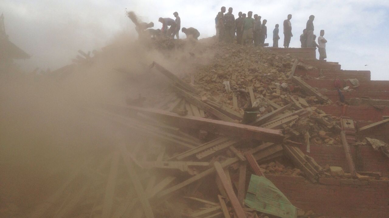 People help with rescue efforts at the site of a collapsed building in Kathmandu.