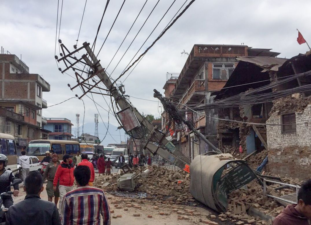 Pedestrians walk past collapsed buildings in Kathmandu on April 25.