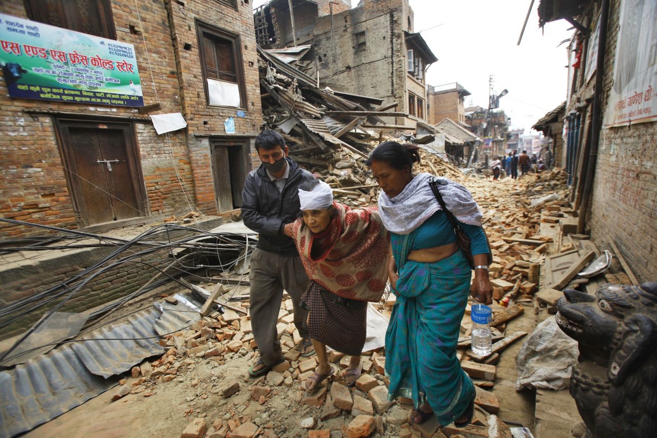 An elderly woman is helped to her home after being treated for her injuries in Bhaktapur on April 26. 