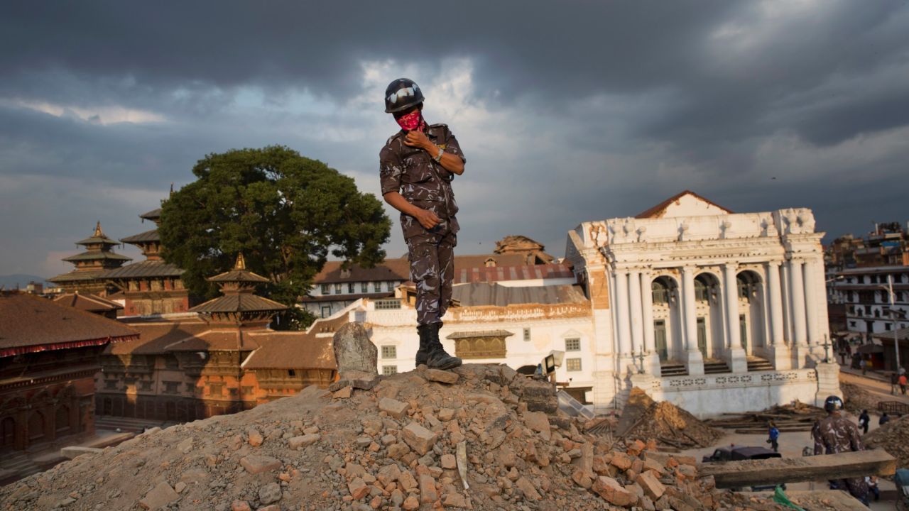A Nepalese policeman stands atop of a rubble at Basantapur Durbar Square .