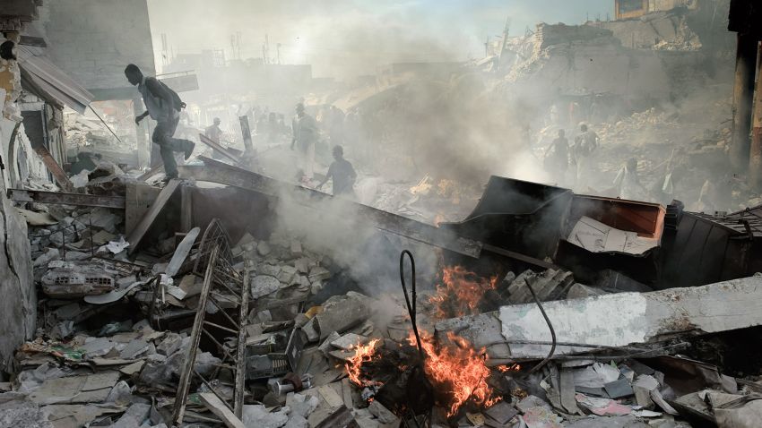 Haitians walk through collapsed buildings near the iron market in Port-au-Prince on January 31, 2010.