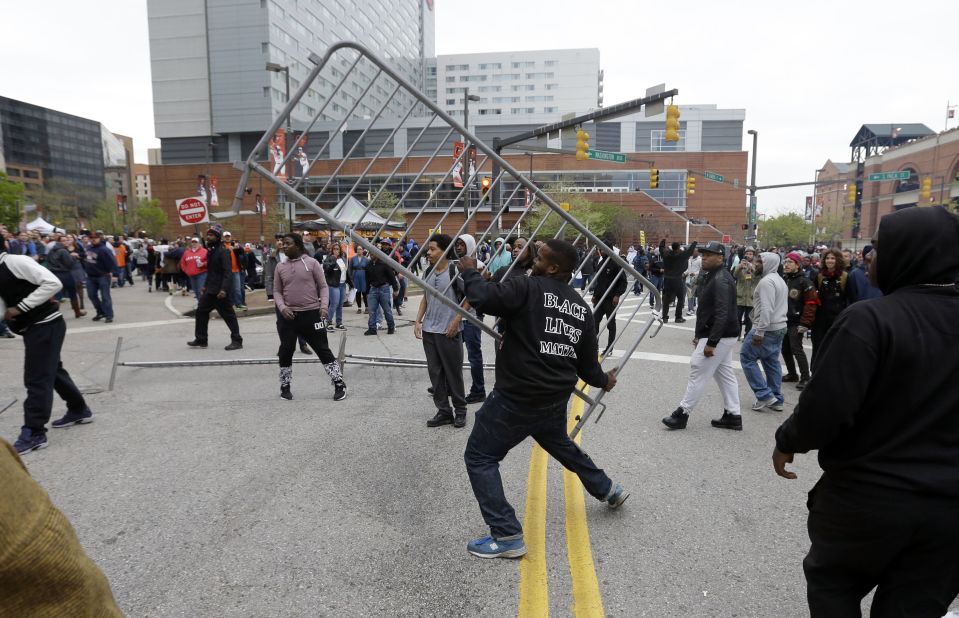 A protester throws a barricade at a bar near Oriole Park at Camden Yards after a rally on April 25.